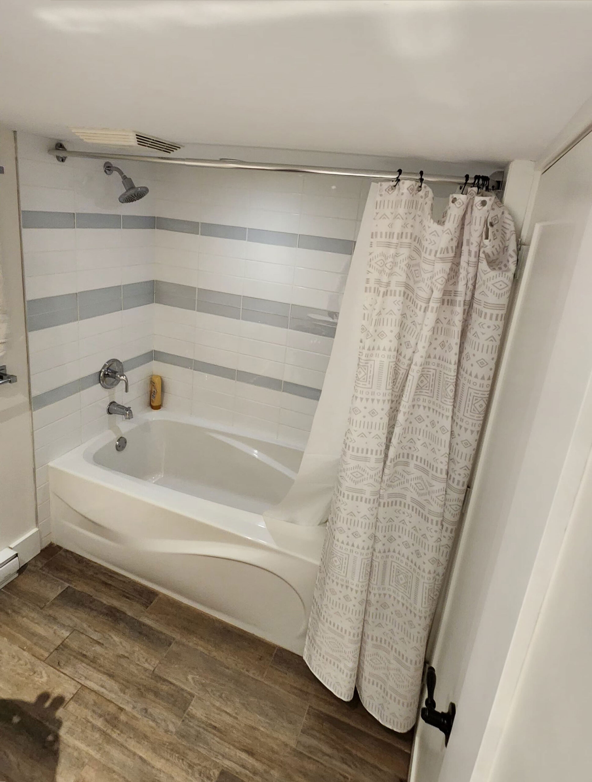 Bathroom renovation before with a white tub and shower curtain taken at a 45 degree angle