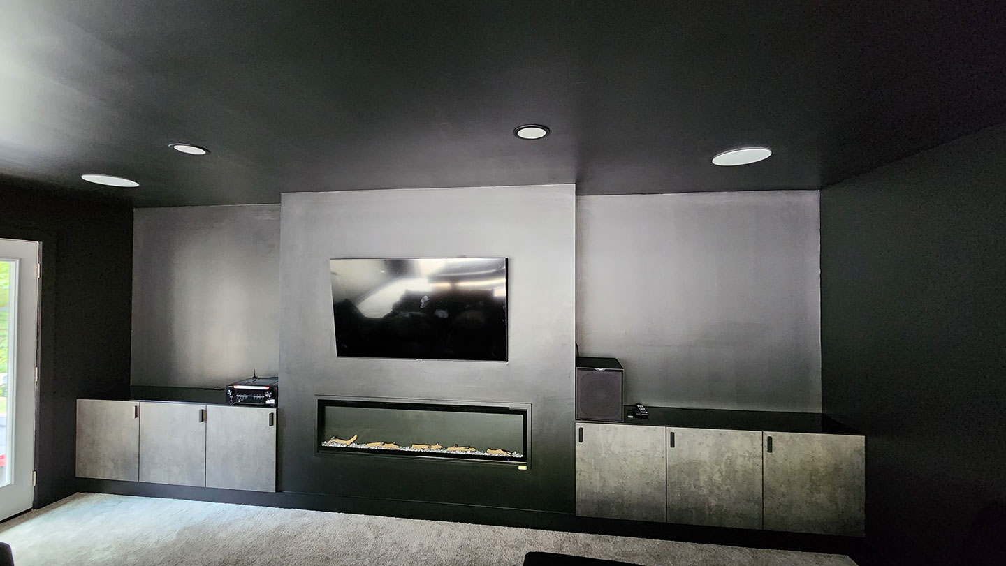 After shot of a garage conversion with an entertainment center, cupboards and a fireplace